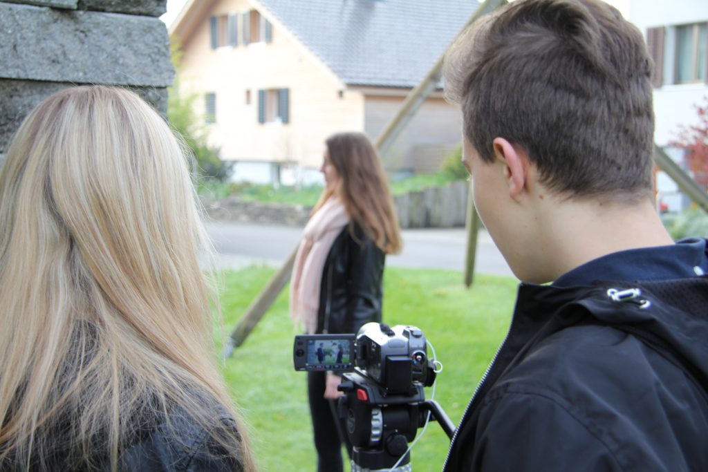 Blick über die Schulter: Schüler filmen eine Darstellerin auf der Wiese