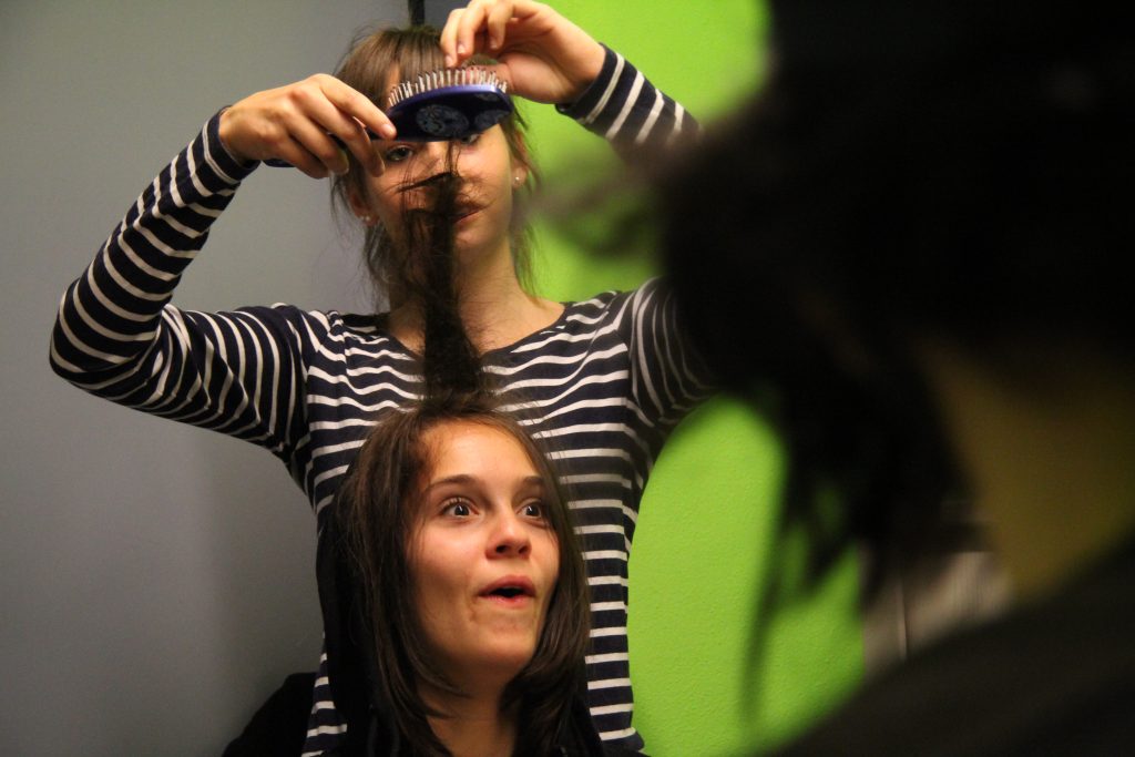 Maske und Frisur: Eine Schülerin frisiert eine Darstellerin vor dem Dreh