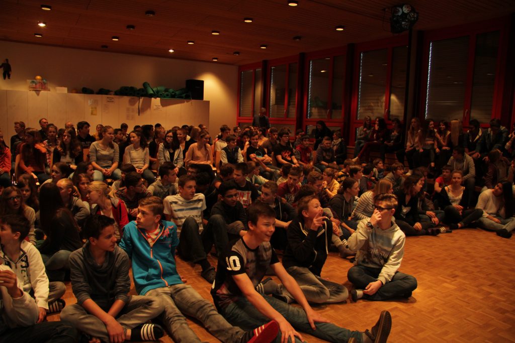 Filmpremiere: Schülerinnen und Schüler schauen in der Aula die fertigen Filme