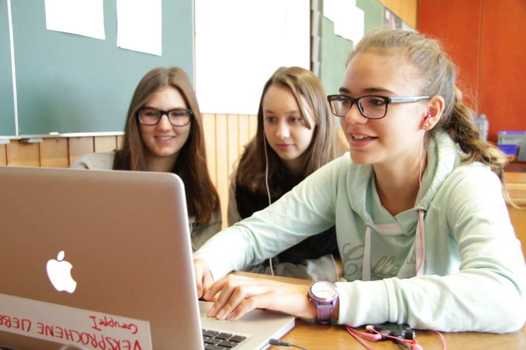 Drei Schülerinnen schneiden gemeinsam ihren Film am Laptop