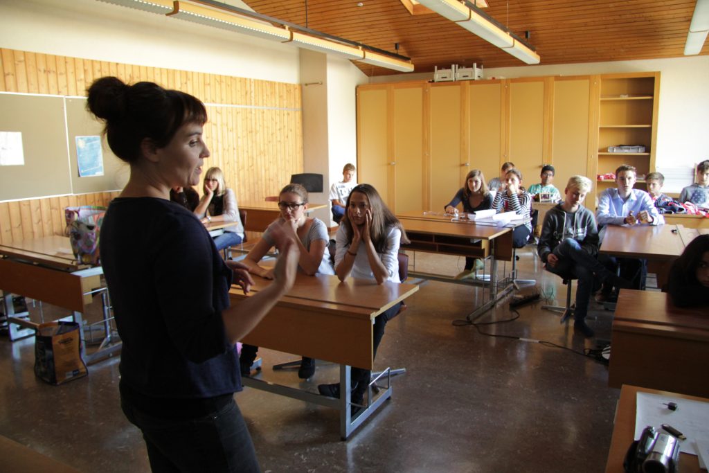 Kursleiterin erklärt der Klasse im Schulzimmer den Ablauf des Filmworkshops