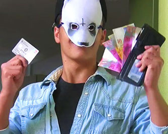 Szene aus einem Musikvideo: Darsteller mit Maske zeigt Geldscheine und Karte